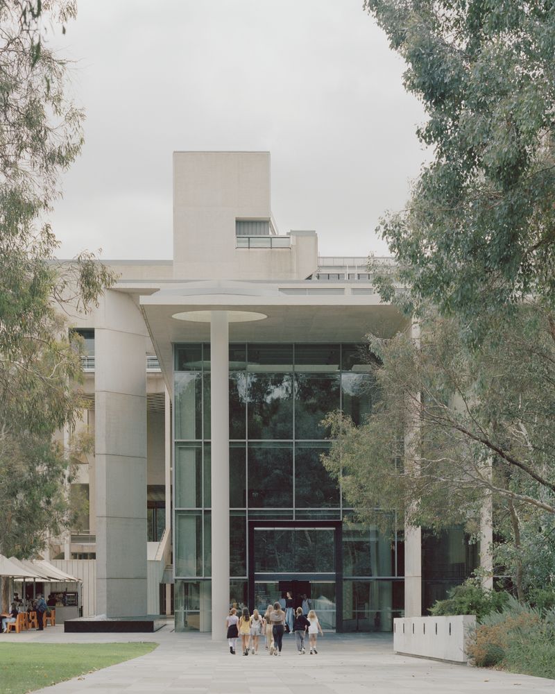 Photo of the exterior to a building with a group of people walking towards the main entrance