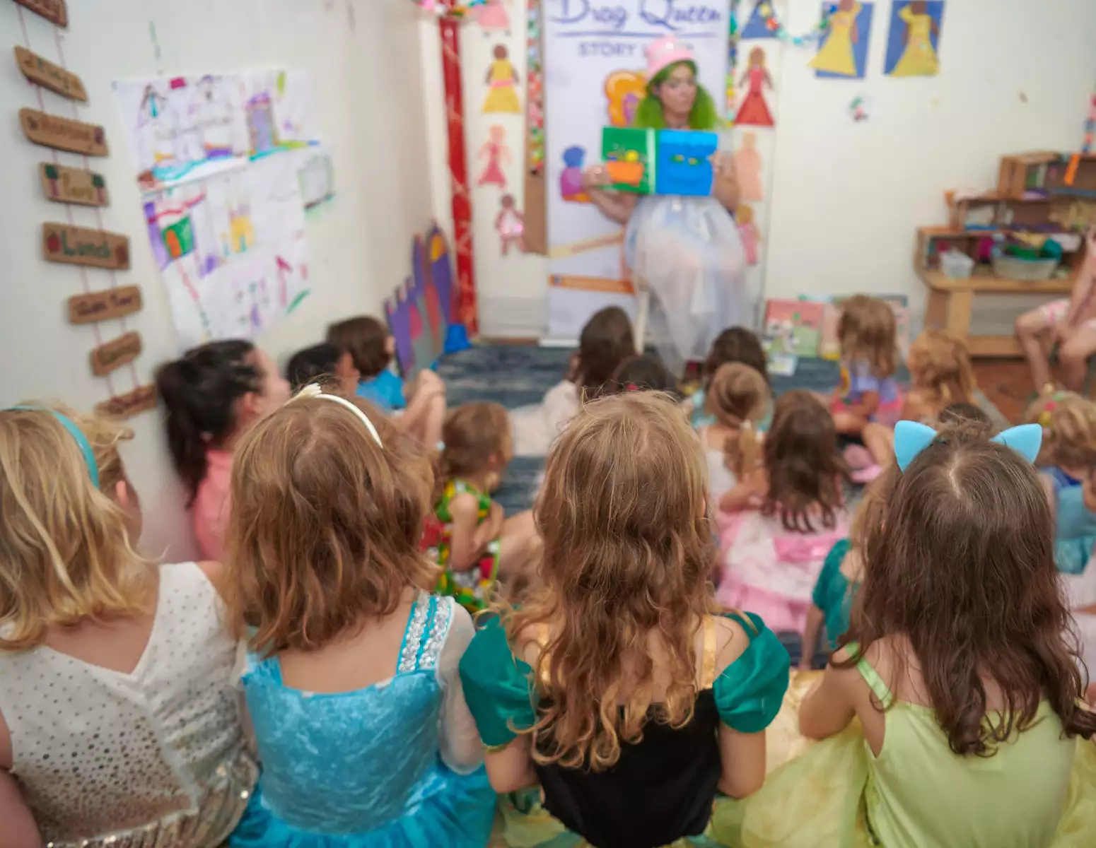Children watch a person in fancy dress read a story