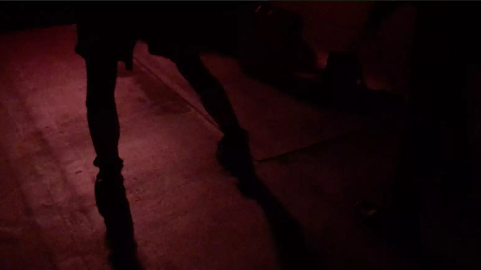 A person dancing in a club obscured by the dark