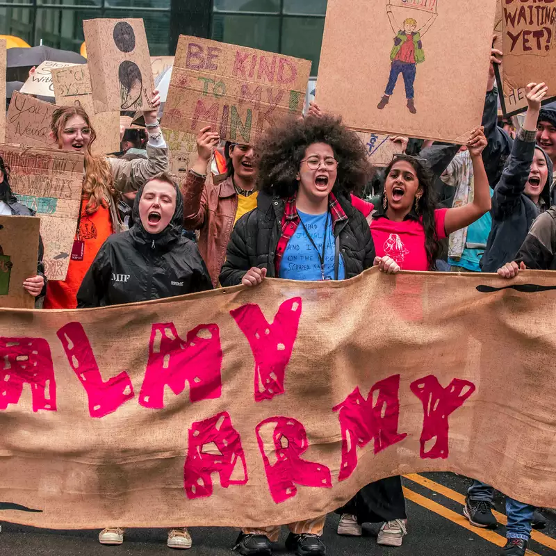 Photograph from a march through Manchester City Centre as part of MIF23. It shows people holding a large banner that reads 'Balmy Army'.