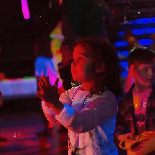 A toddler clapping their hands on a dance-floor at a disco