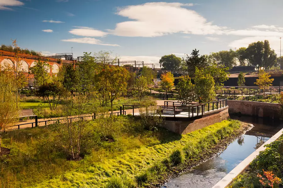 A picture of a park with lots of greenery and a small river flowing through the middle