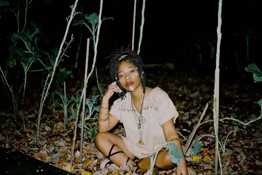 Meduulla - one of the Factory Sounds cohort for 2023 - sits cross legged outdoors among plants at nighttime