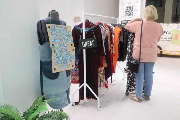 Photo of someone browsing a rack of clothing at a clothes swap