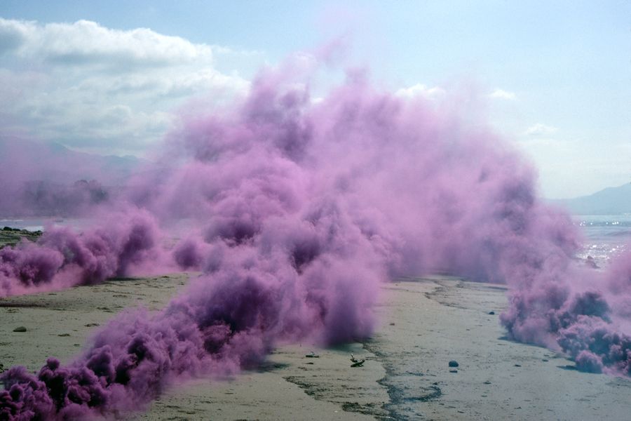 Purple smoke engulfs an outdoor location