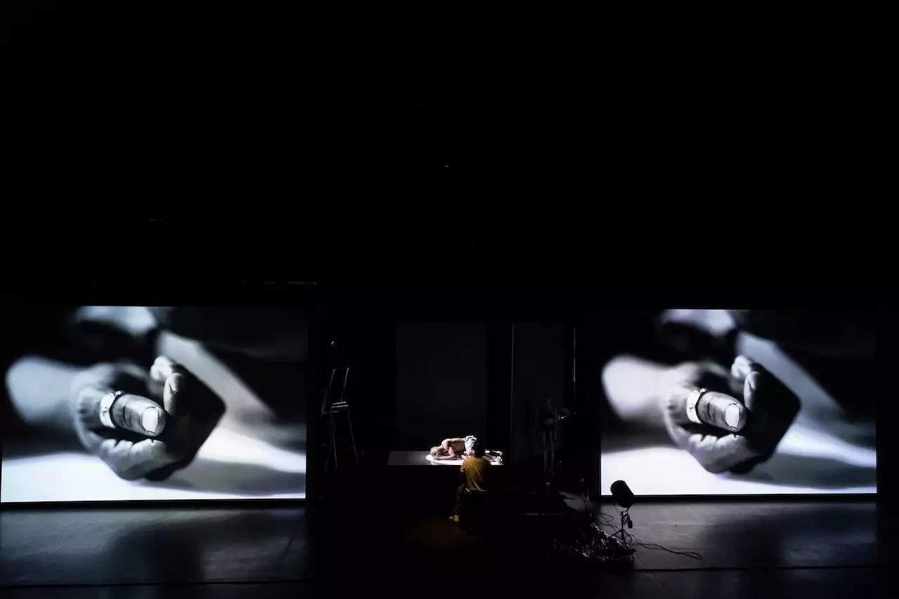 Benji Reid's black and white photograph of a hand, on two screens on stage