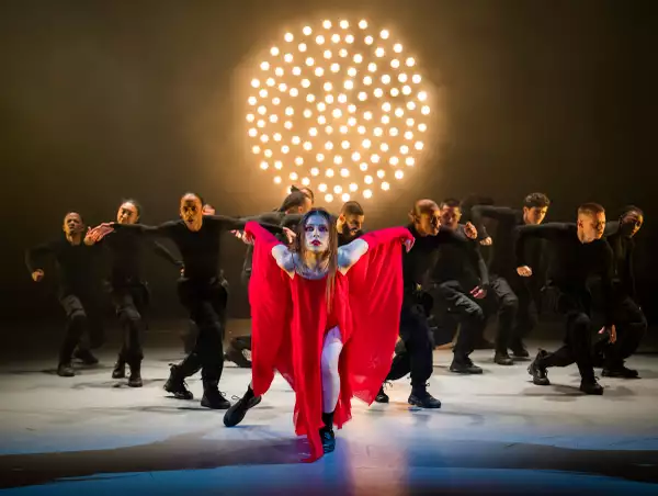 Dancer wearing a red dress surrounded by dancers in black clothing in Free Your Mind