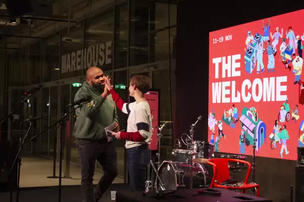 An adult and child high-five on stage during The Welcome