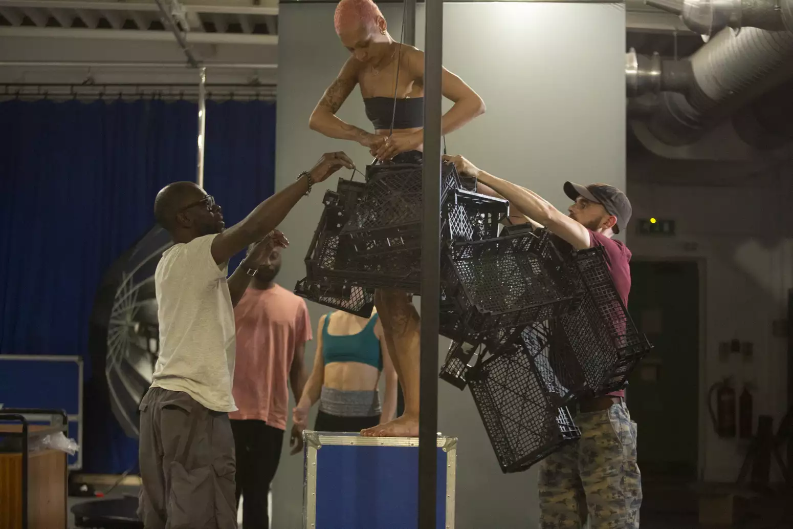 Photo of a group of people attaching several crates to a performer