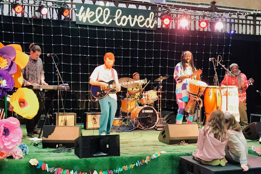 Sens Sagna & the Kajamor Family perform on stage while two children watch