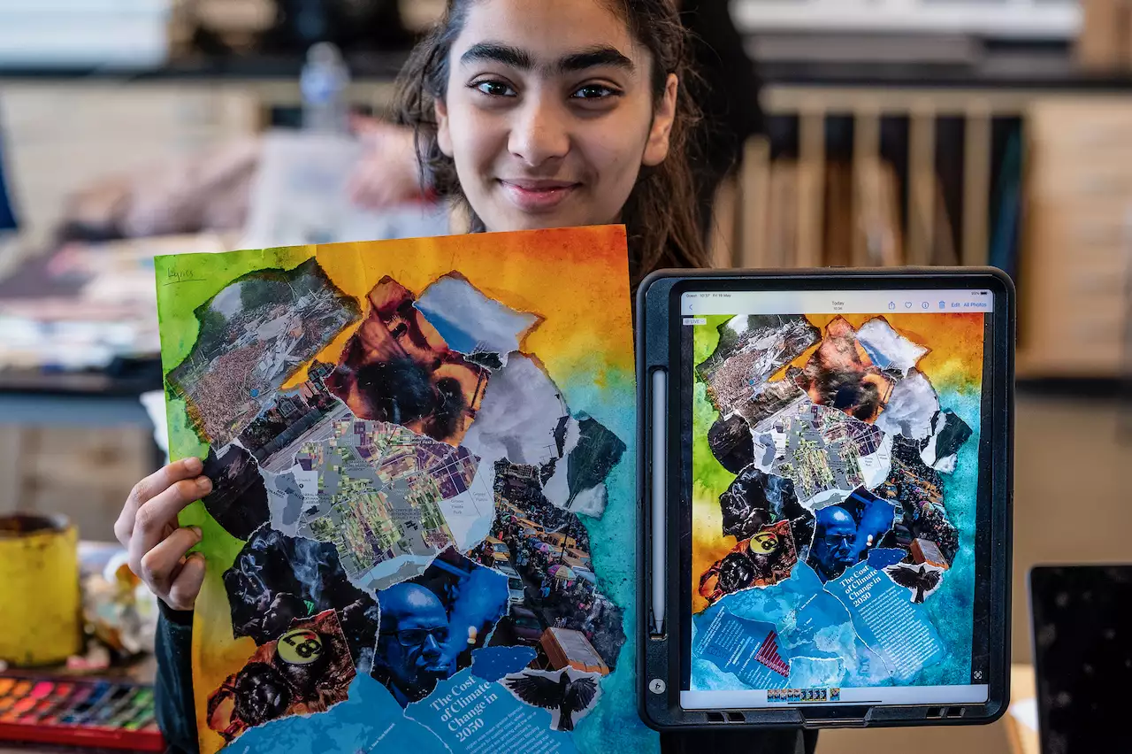 A child holds up their artwork smiling