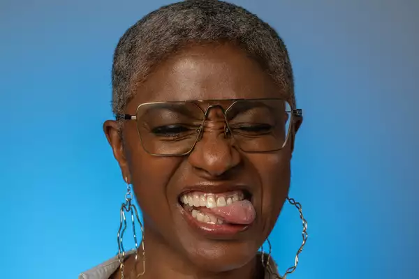 DJ Paulette wearing big hoop earrings on a bright blue background