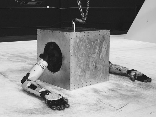 A robot in the shape of a cube sitting on a white floor