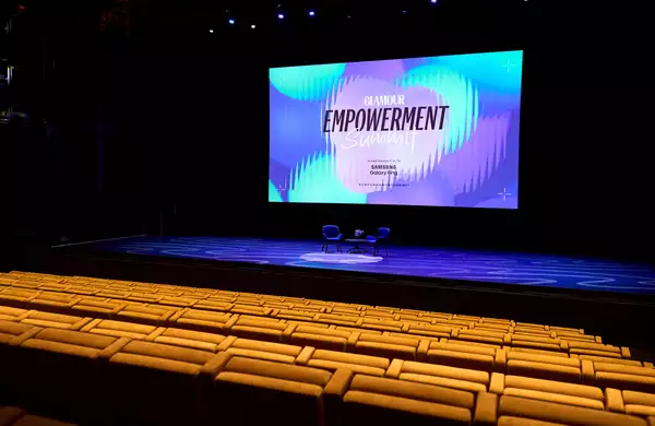 Empty seats in the Hall. The stage has two empty chairs on it ready for an event. The screen behind says 'Glamour Empowerment Summit'.