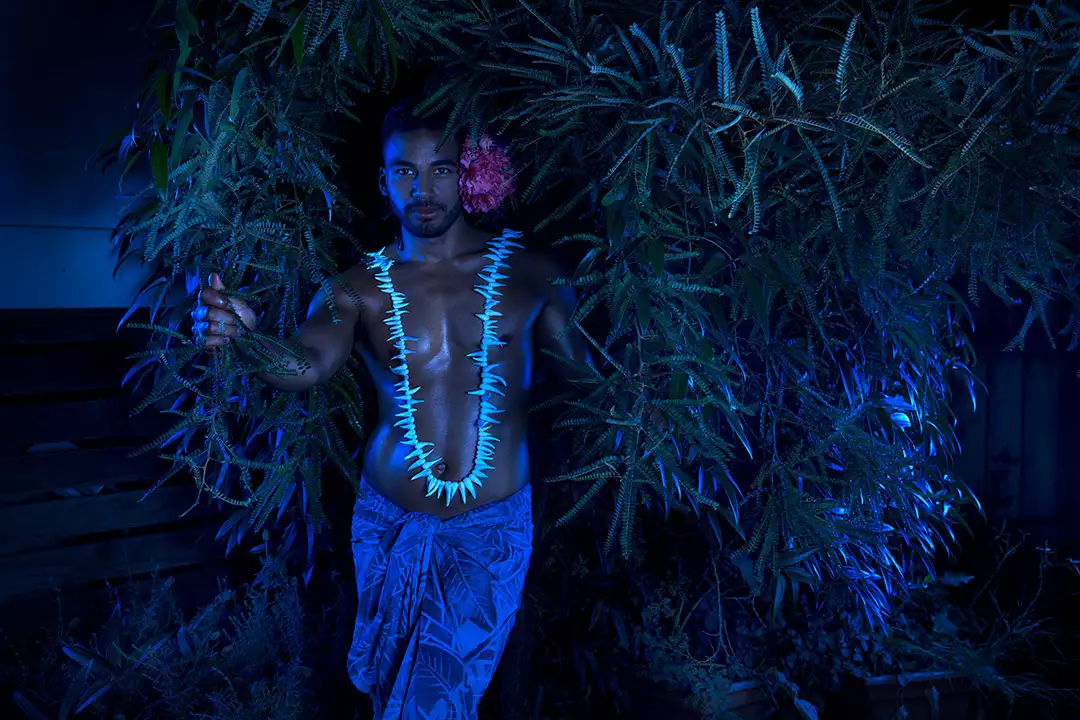 Fafswag artist posing in front of leaves under deep blue lighting