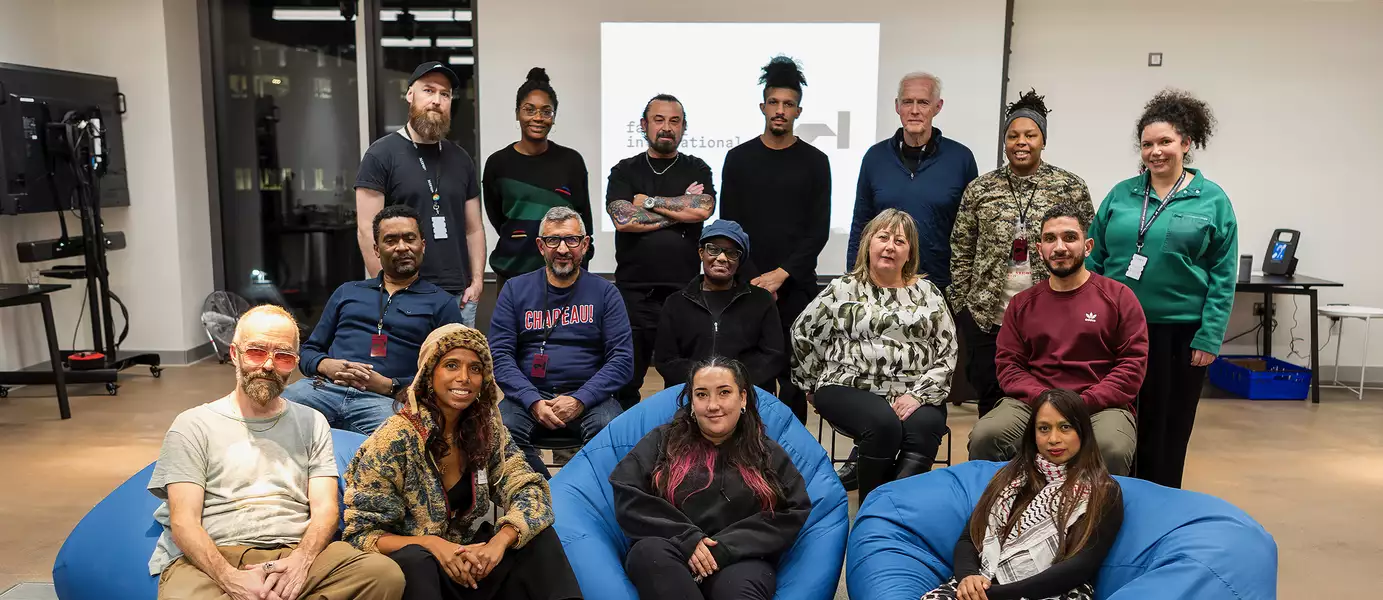 Group photo of Fusion Factory and BRiGHTBLACK. Some people are stood up; others are sat on three blue beanbags.