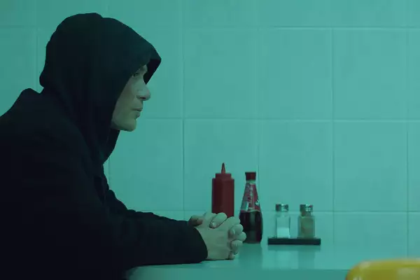 All this this unreal time thumbnail of side view of man in a hoodie sat at a table