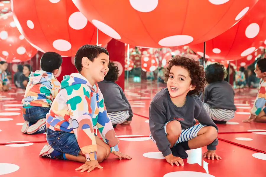 Two young children enjoy a Yayoi Kusama artwork