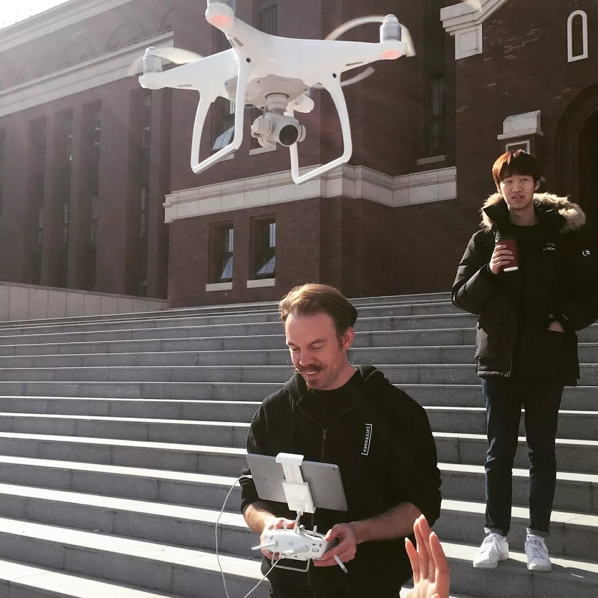 Josh Harle operating a drone on a flight of steps outside.