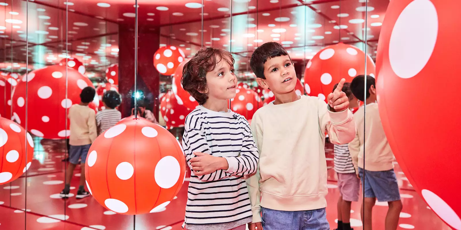 Two children enjoy a red and white polka dot installation by Yayoi Kusama