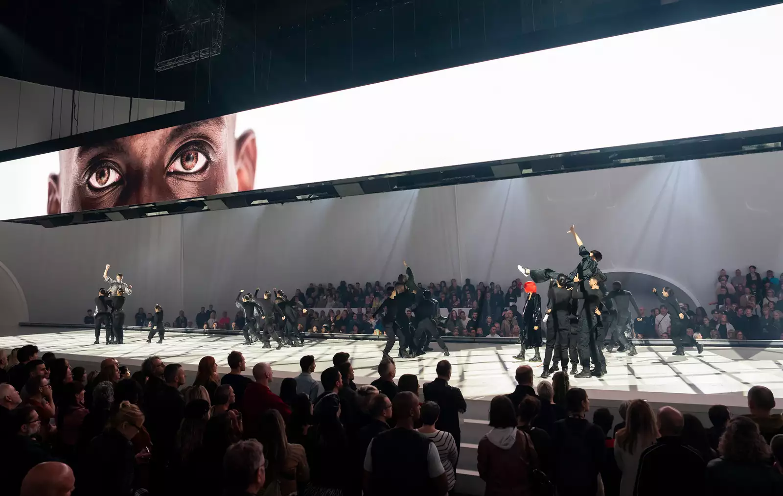 Dancers perform under a screen showing a person's eyes for Free Your Mind