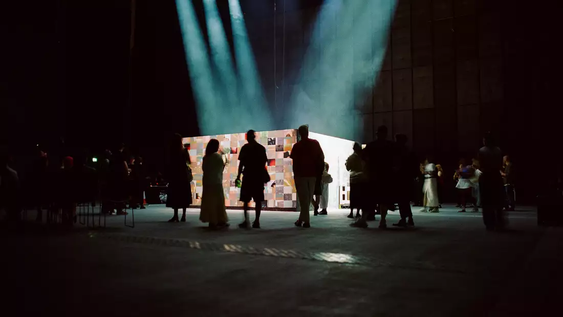 A group of people watching 54: Manchester's installation in the Warehouse.