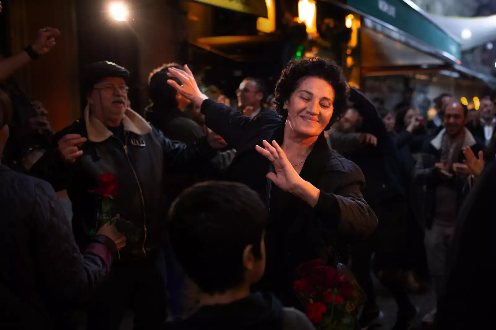 Still from Crossing. A character dancing and smiling with their eyes closed in a crowd of people.