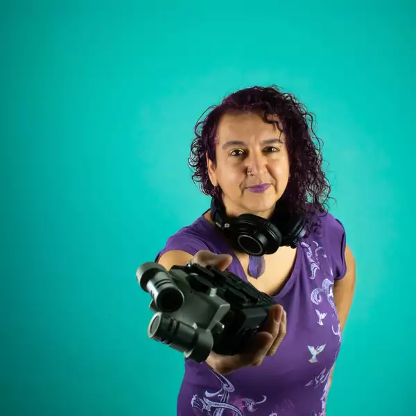 Headshot of Maya Chowdhry on a turquoise background