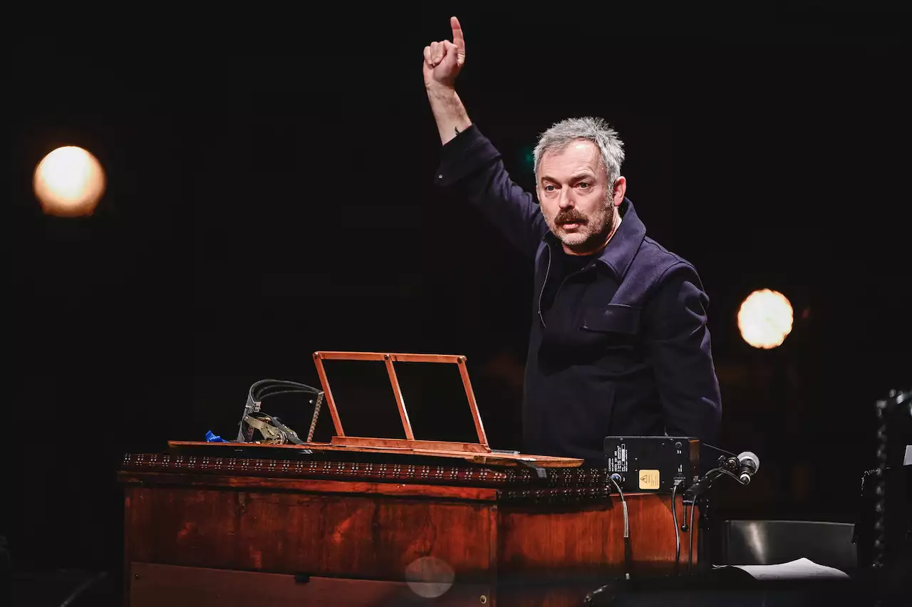 An orchestra member playing piano with one hand in the air