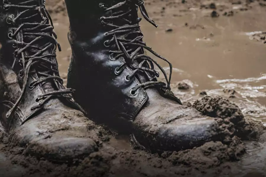 Black lace-up boots stuck in mud