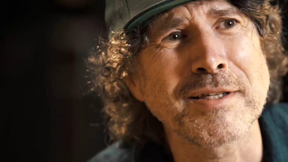 Close up of Gruff Rhys' face, wearing a grey peaked hat