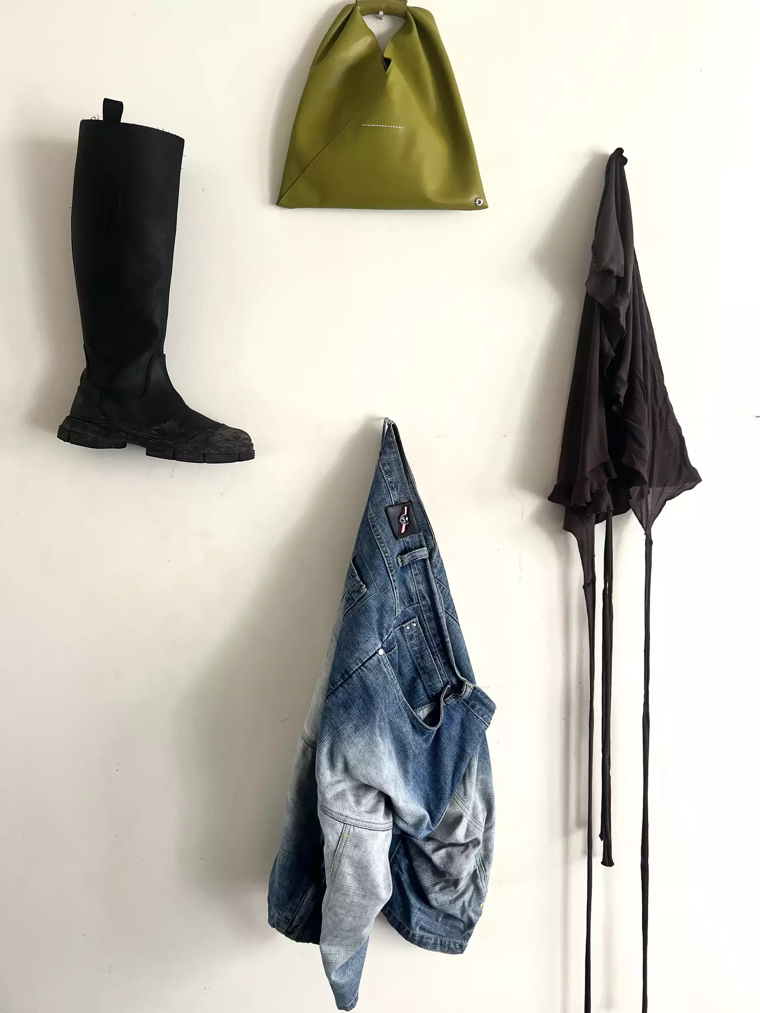 A selection of clothes from Zora Jade Khiry laid out: a knee-high boot, handbag, black top and denim shorts