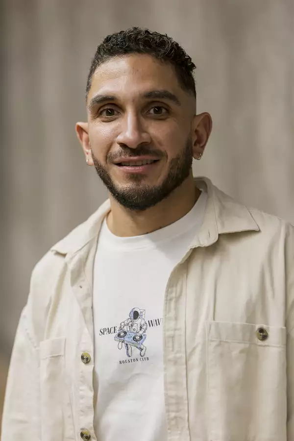Portrait photograph of Roger Muñoz wearing an open cream shirt over a white t-shirt
