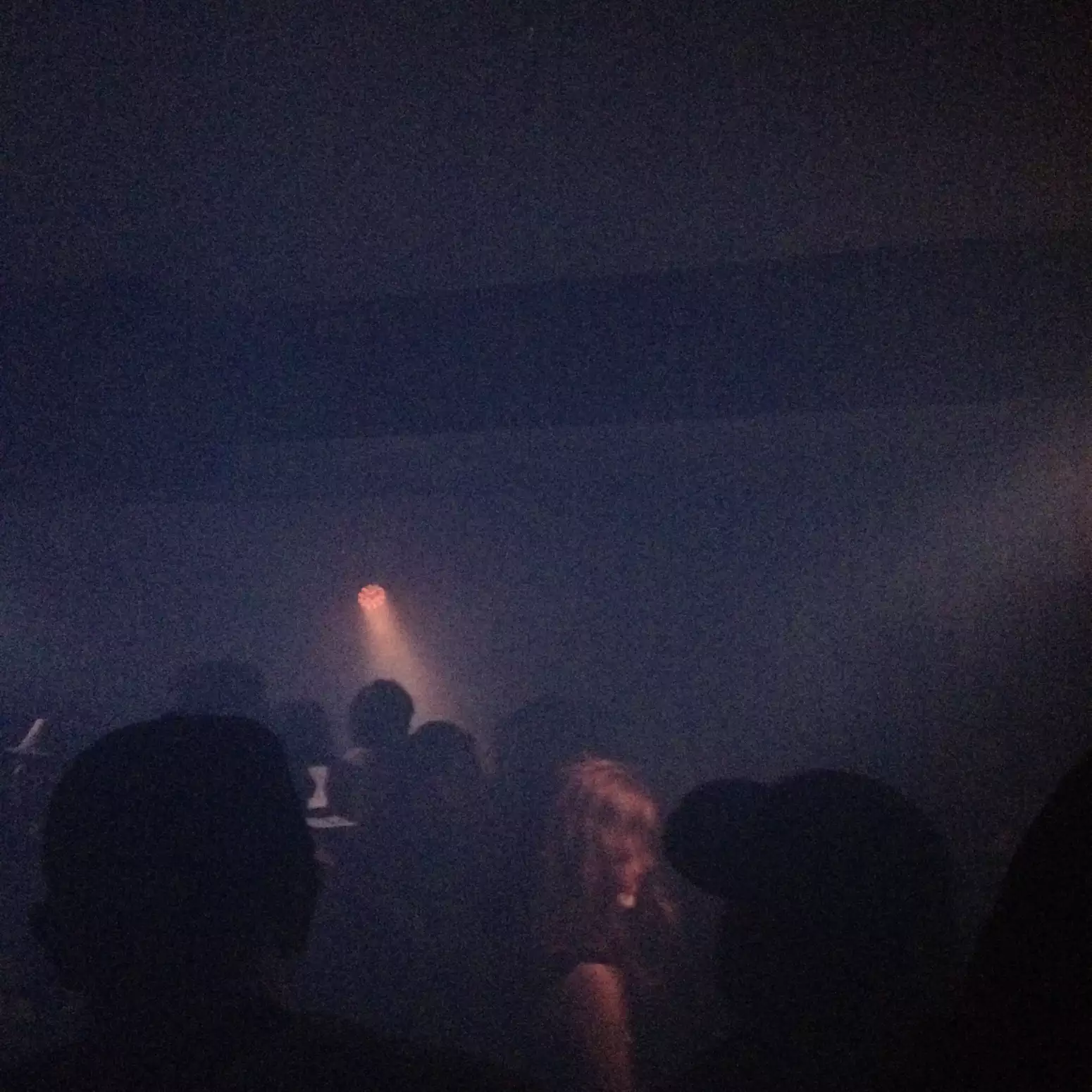 A single spotlight illuminates a dancefloor at a rave