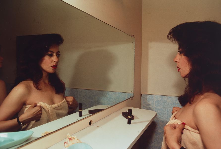 Cibachrome colour photograph of a woman looking at herself in a mirror. She is wrapped in a towel.