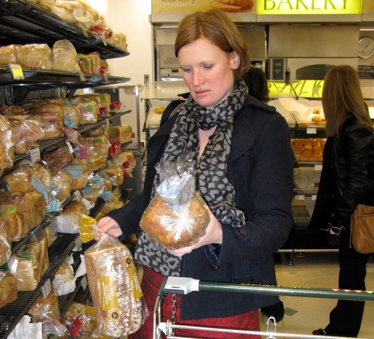 Shopper looks at two loaves of bread as if comparing them