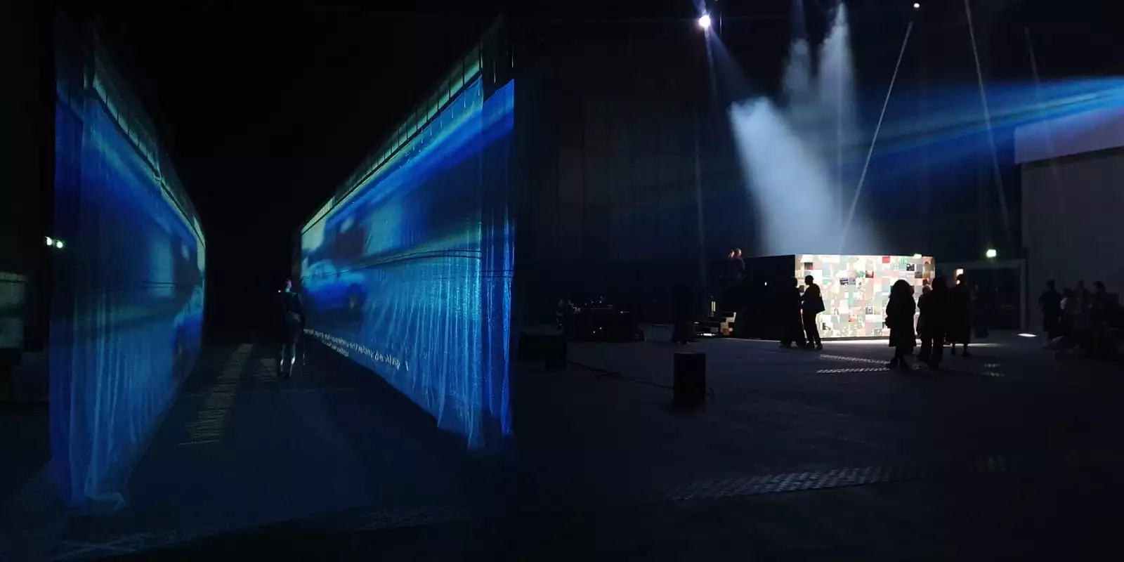 54: Manchester's installation in the warehouse – showing a fabric walkway with a film projected on to it and an enclosed, collaged box with performers inside