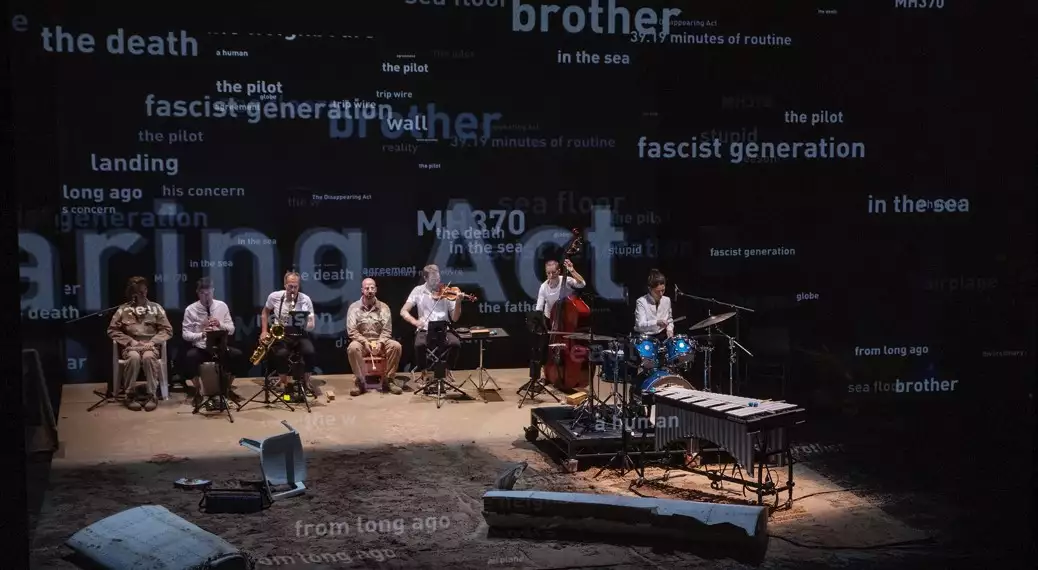 Musicians on stage with lots of words behind them on a screen