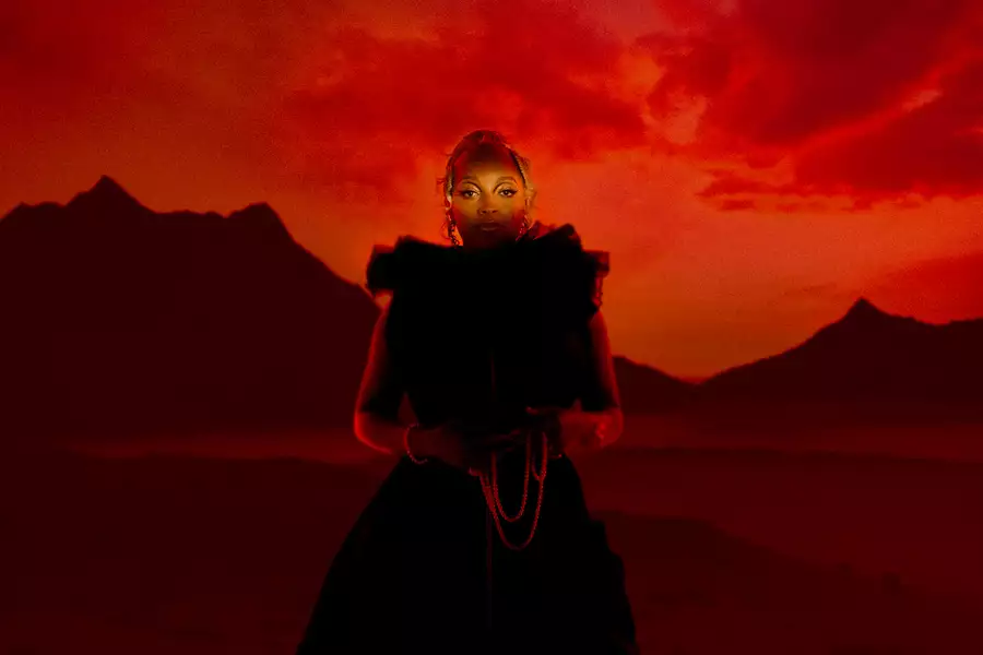 Photo of Nubya Garcia standing in front of a red sky with a backdrop of a mountain ridge