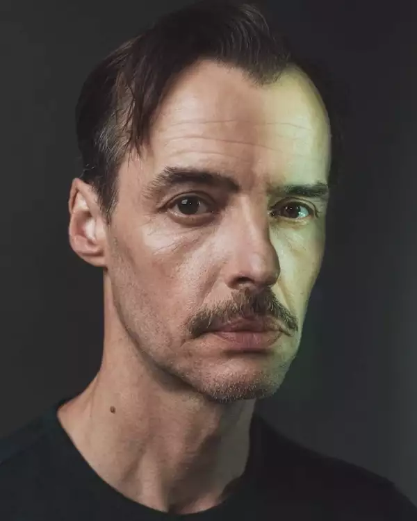 Headshot of Paul Hilton wearing a black top