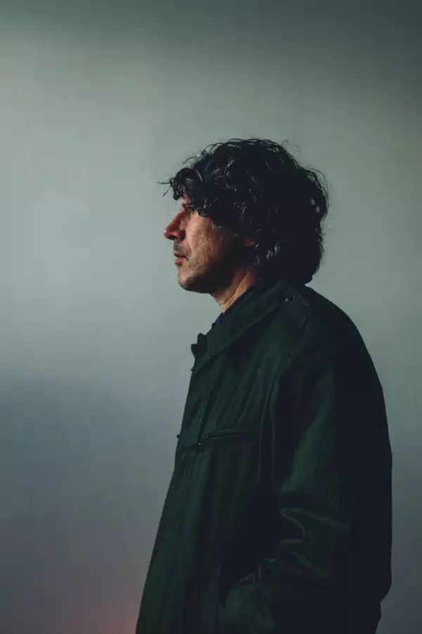 Gruff Rhys in profile against a blue background