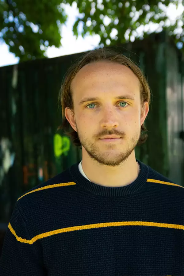 Oliver Baines in a blue and yellow striped jumper